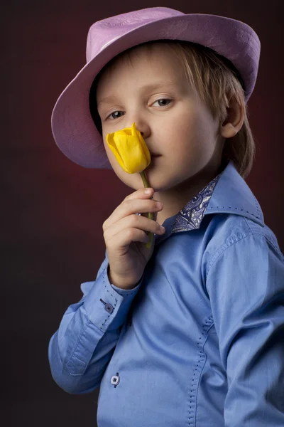 Menino de chapéu rosa com tulipas amarelas — Fotografia de Stock