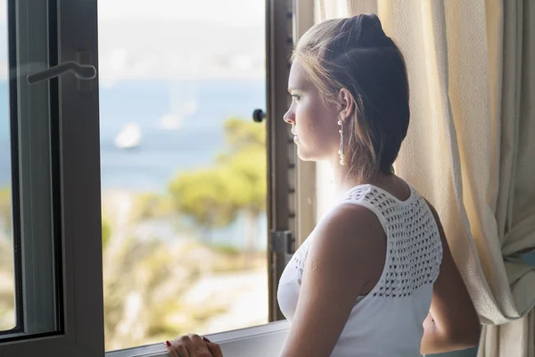 Junge Frau steht am Fenster — Stockfoto