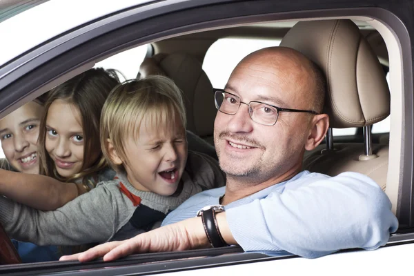Huppy padre con niños en un coche Imágenes de stock libres de derechos