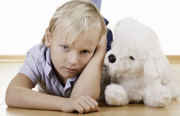 Menino loiro com cão de brinquedo branco — Fotografia de Stock