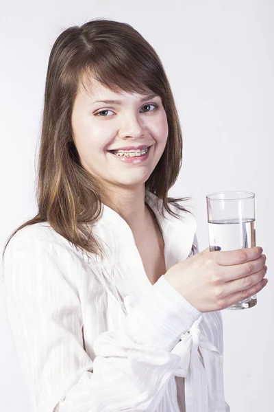 Giovane donna con bicchiere d'acqua su un bianco — Foto Stock