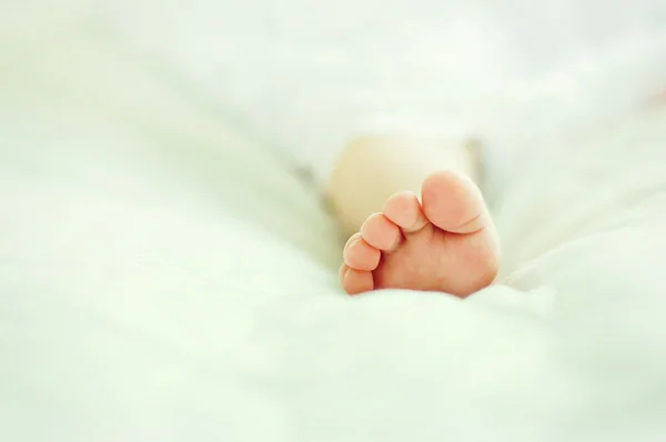 Petit pied d'un bébé sur une surface blanche — Photo