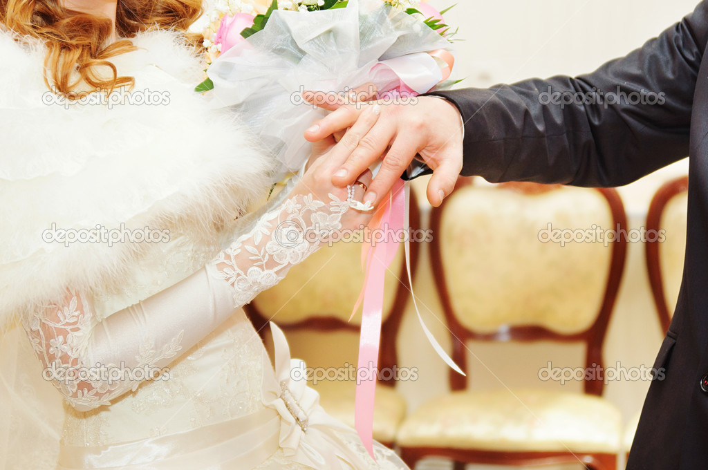 Groom putting ring on bride