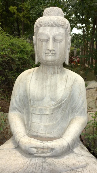 Estátua de Buda antiga contra madeiras verdes — Fotografia de Stock