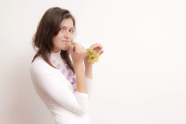 Mladá žena jíst hrozny — Stock fotografie