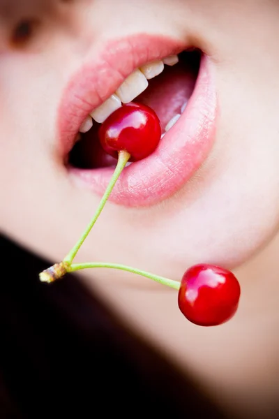 Beautiful girl's lower part of face with two red cherries in mouth — Stock Photo, Image