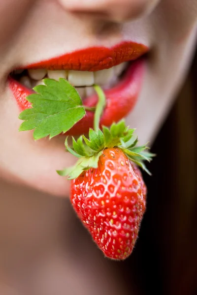 Vrouwelijke mond met een aardbei — Stockfoto