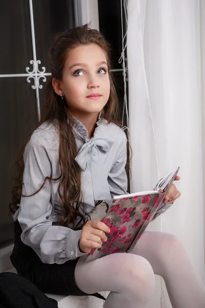 Νεαρό κορίτσι που κάθεται σε ένα windowsill με ένα βιβλίο — Φωτογραφία Αρχείου