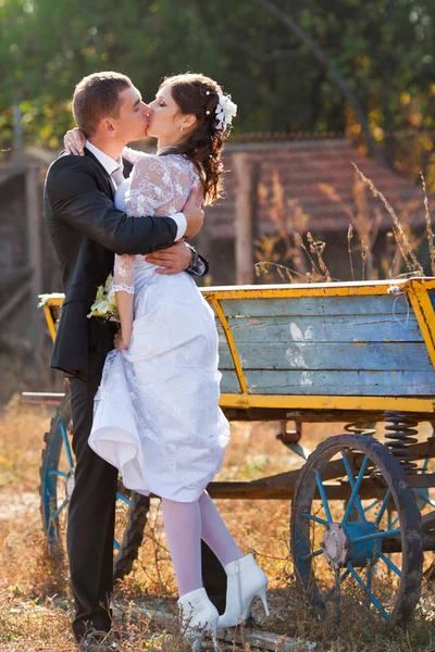 Brudgummen och bruden stå och kyssa nära fordonet — Stockfoto