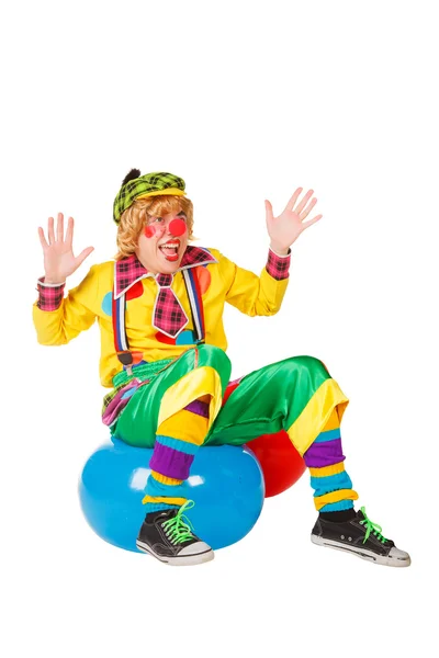 Смішний клоун сидить на блакитному м'ячі — стокове фото