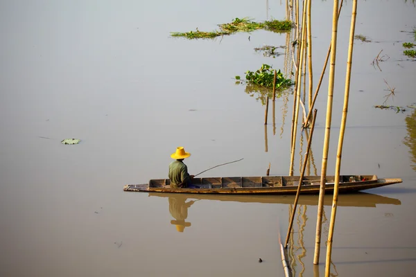 Pescador nativo asiático sentado no barco com bambu — Fotografia de Stock