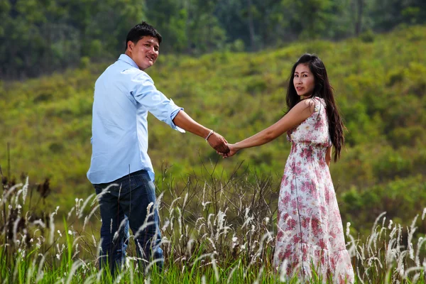 A Couple Walking Through A Grassland, holding hands — Stock Photo, Image