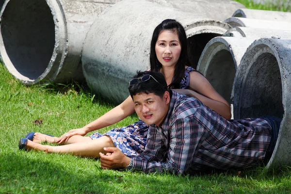 Romantic couple relaxing in cement pipe in park — Stock Photo, Image
