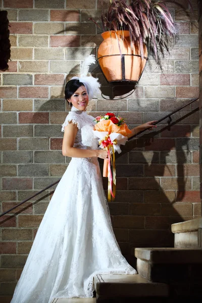 Mireasă elegantă cu buchet de nuntă peste peretele de cărămidă — Fotografie, imagine de stoc