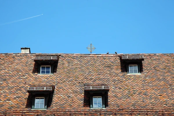 Mavi gökyüzü arka plan üzerinde kepenkli pencereler ile çatı — Stok fotoğraf