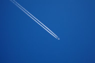 Mavi gökyüzünde uzun bir jet uçağı yolu
