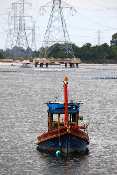 Wooden fishing boat and electrical tower in industrial area — Stock Photo, Image