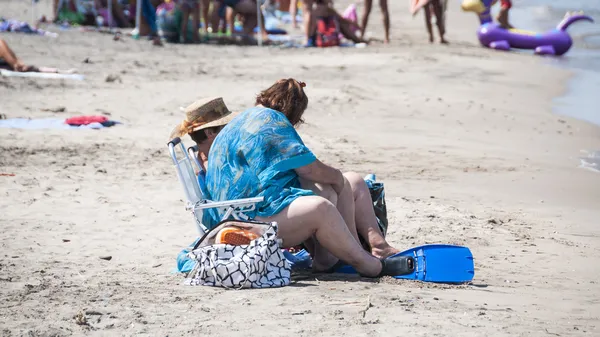 Gruba kobieta siedzi na plaży nad morzem — Zdjęcie stockowe