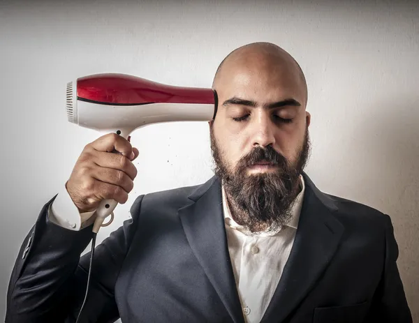 Man met baard en vest met hairdraier en grappige expressies — Stockfoto