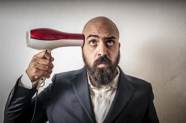 Man met baard en vest met hairdraier en grappige expressies — Stockfoto