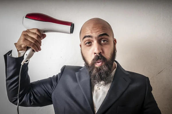Man met baard en vest met hairdraier en grappige expressies — Stockfoto