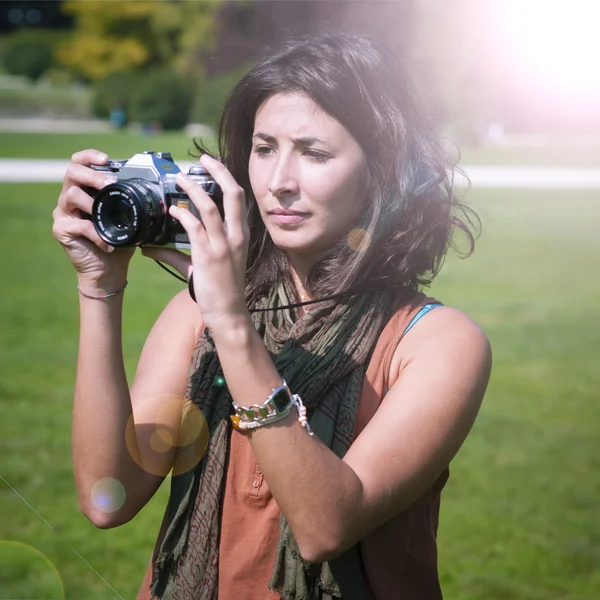 Beautiful girl with scarf and camera on the lawn — Stock Photo, Image
