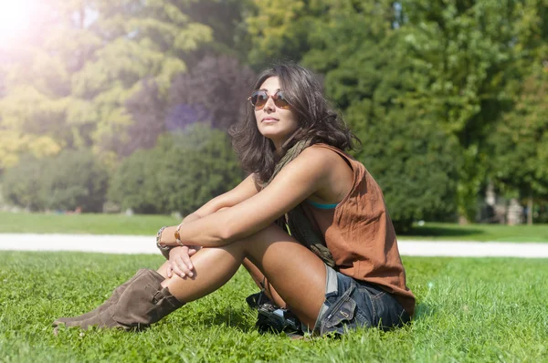 Красива дівчина з шарфом і сонцезахисними окулярами на газоні — стокове фото
