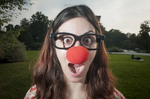 Surprised clown girl with red nose at the park — Stock Photo, Image