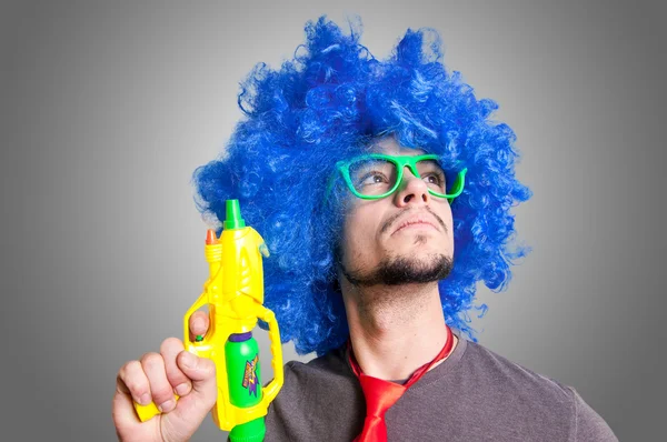 Cara engraçado com peruca azul e pistola de água — Fotografia de Stock