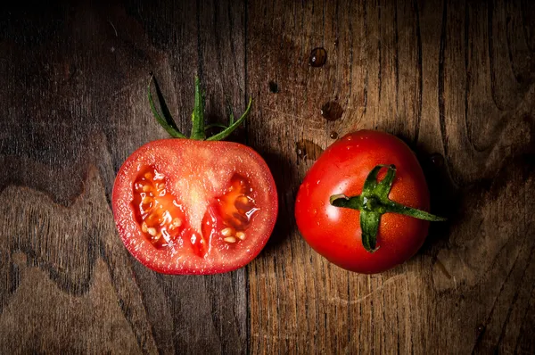 Pomodori interi e interi su legno Foto Stock