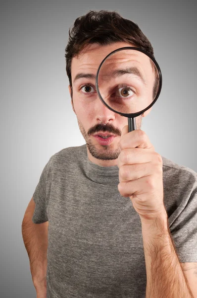 Man looking through a magnifying lens — Stock Photo, Image