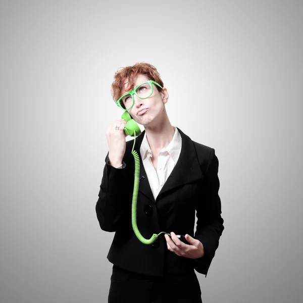 Сомнительная деловая женщина с зеленым телефоном — стоковое фото