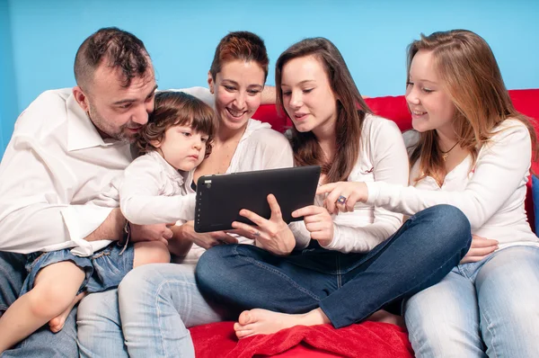 Familia feliz en el sofá usando la tableta — Foto de Stock