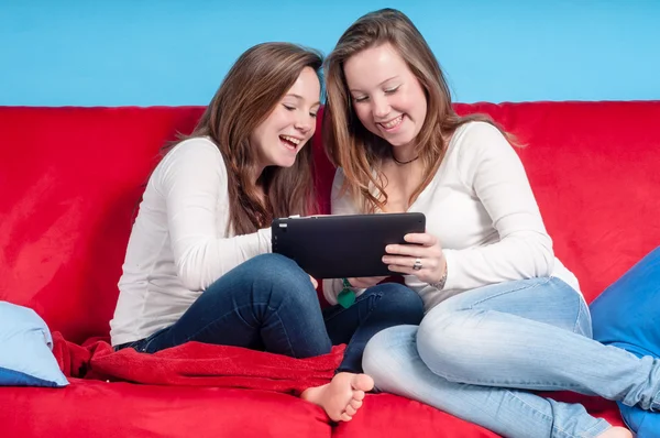 Happy teenagers using tablet on the couch at home — Stock Photo, Image