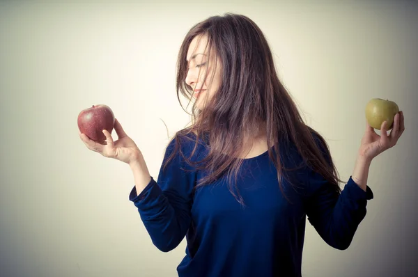 Beautiful woman choosing red or yellow apples — Stock Photo, Image