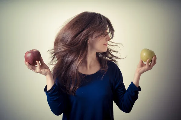 Beautiful woman choosing red or yellow apples — Stock Photo, Image