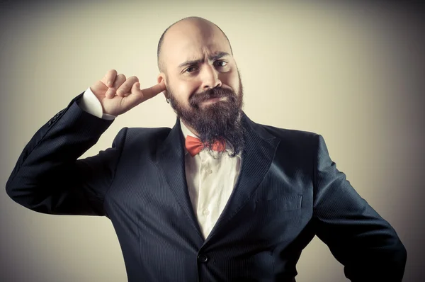 Gracioso hombre barbudo elegante con el dedo en la oreja — Foto de Stock