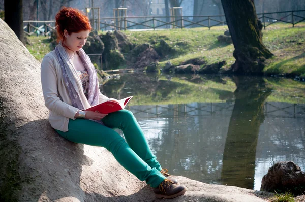 Красивая рыжая молодая женщина читает книгу — стоковое фото