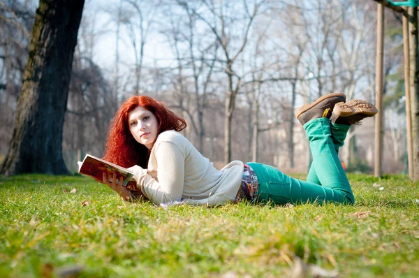 Красивая рыжая молодая женщина читает книгу — стоковое фото