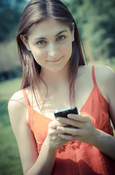 Hermosa modelo joven en el teléfono en el parque — Foto de Stock