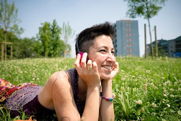 Красивая хипстерская коротковолосая женщина слушает музыку в парке — стоковое фото