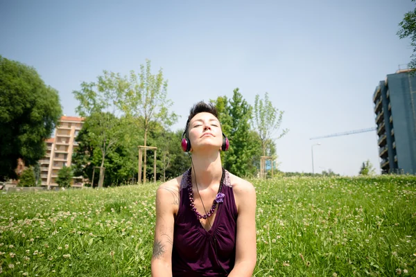 Hermosa hipster pelo corto mujer escuchando música en el parque —  Fotos de Stock