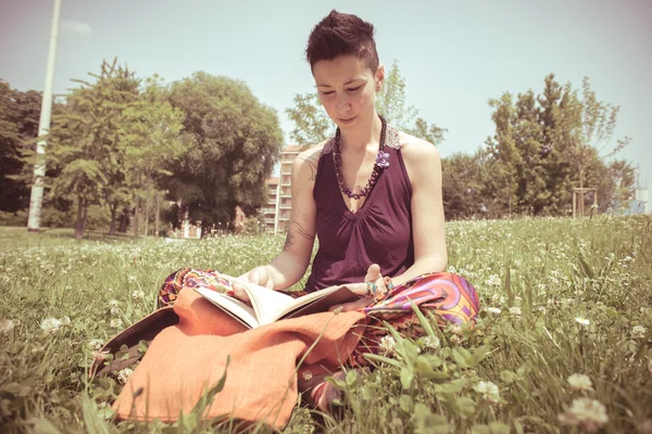 Hermosa hipster pelo corto mujer lectura libro en el parque —  Fotos de Stock
