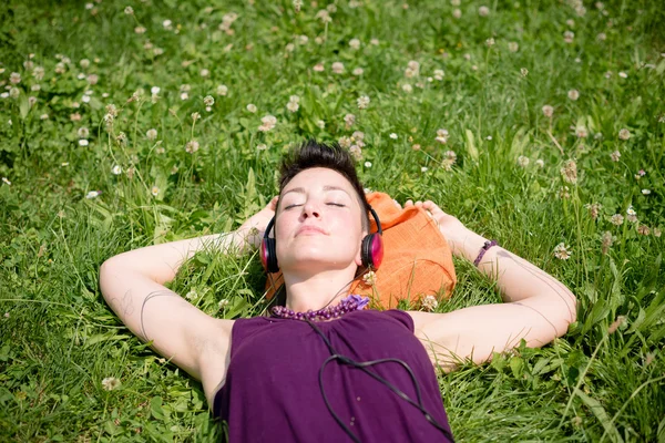 Hermosa hipster pelo corto mujer escuchando música en el parque —  Fotos de Stock