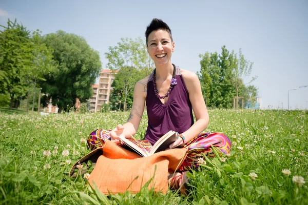 Красивая хипстерская коротковолосая женщина читает книгу в парке — стоковое фото