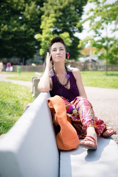 Bella hipster capelli corti donna ascoltare musica nel parco — Foto Stock