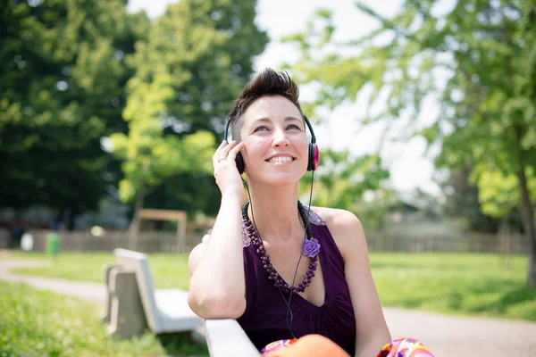 Belle femme hipster cheveux courts écouter de la musique dans le parc — Photo