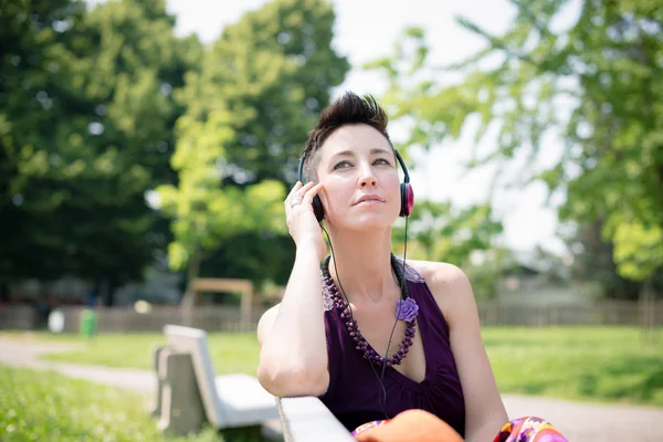 Bela hipster cabelo curto mulher ouvir música no parque — Fotografia de Stock