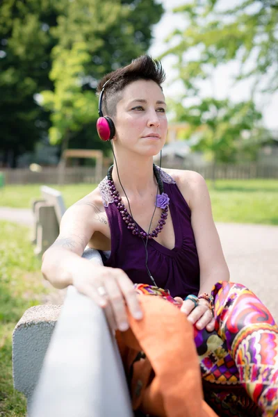 Vacker hipster kort hår kvinna lyssnar musik i parken — Stockfoto