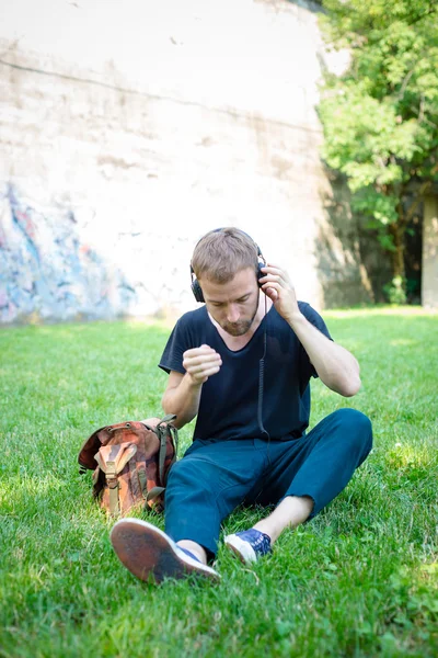Bederní moderní stylový blondýna člověka poslech hudby v parku — Stock fotografie